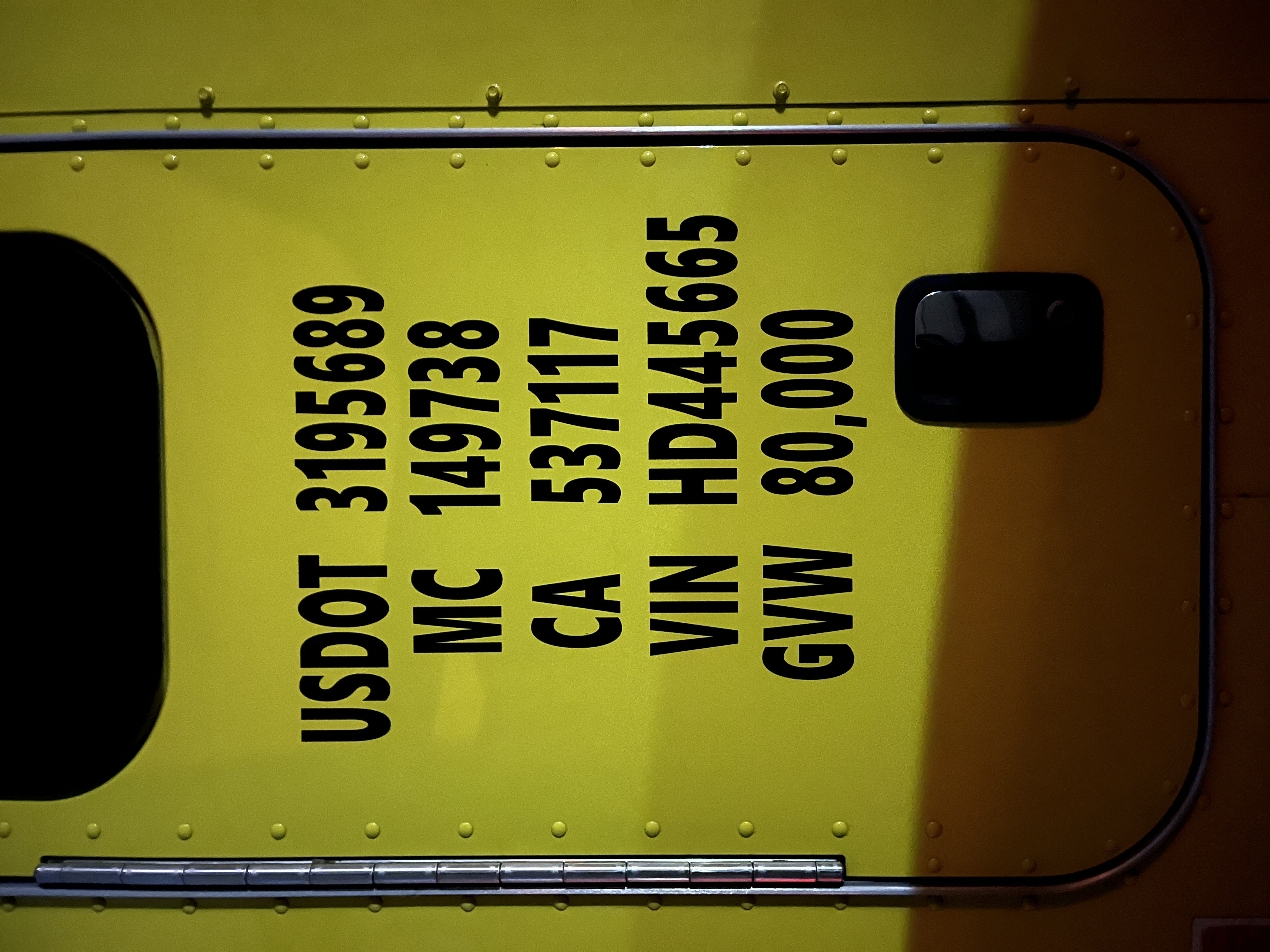 Mobile Truck Lettering installing a decal on a yellow truck